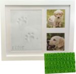 White wooden picture frame with a clay paw print impression and two photo slots, with a stencil kit beside it.