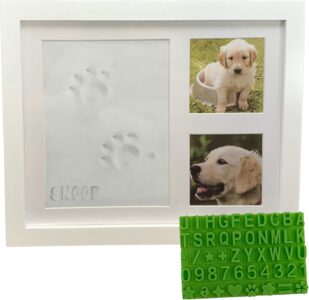 White wooden picture frame with a clay paw print impression and two photo slots, with a stencil kit beside it.