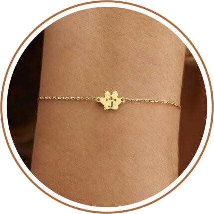Close-up of a gold-plated DONYUDE dog paw initial charm bracelet on a white background, suitable for women.