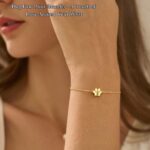Close-up of a gold-plated DONYUDE dog paw initial charm bracelet on a white background, suitable for women.