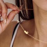 Close-up of a DONYUDE gold-plated necklace featuring a dainty cat's head pendant with the initial 'S' on a polished chain.