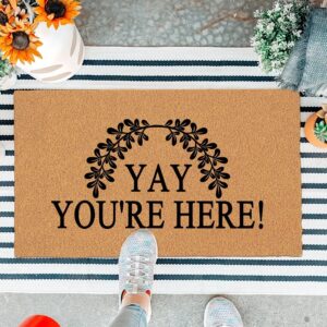 A colorful rectangular doormat with the humorous text "Yay You're Here!" in bold letters, set against a bright background.