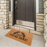 A colorful rectangular doormat with the humorous text "Yay You're Here!" in bold letters, set against a bright background.
