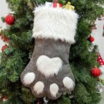 A single grey pet paw shaped Christmas stocking from Sexybody, hanging, with a white cuff and a loop for hanging.