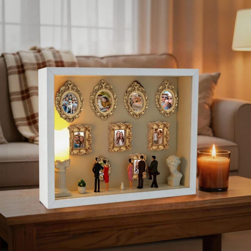 White XINGZUAN Museum of Us DIY Shadow Box Kit on a tabletop, displaying mini gold frames, figurines, and an LED light.