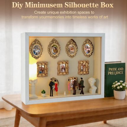 White XINGZUAN Museum of Us DIY Shadow Box Kit on a tabletop, displaying mini gold frames, figurines, and an LED light.
